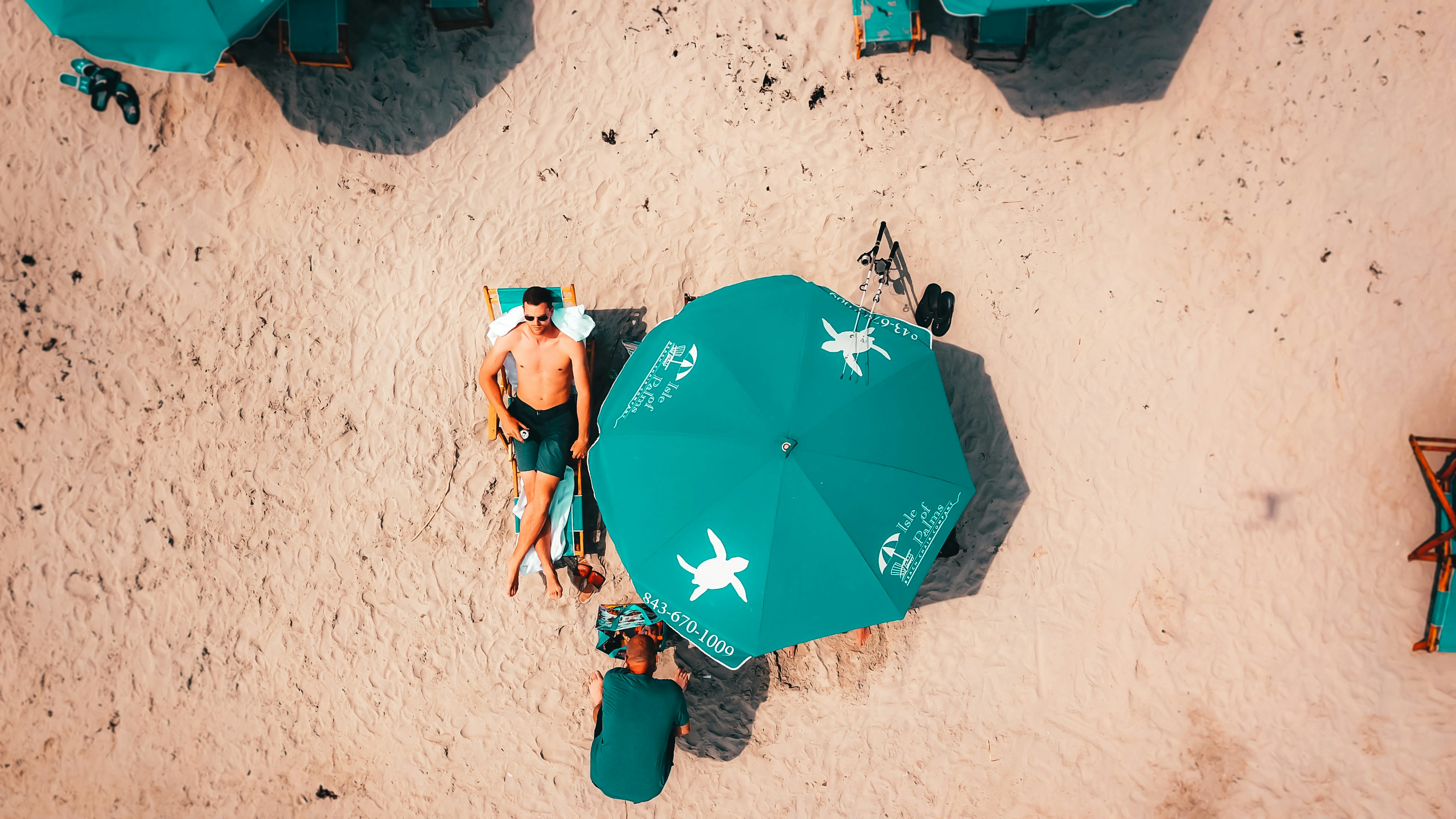 man lying on lounge under umbrella during daytime \